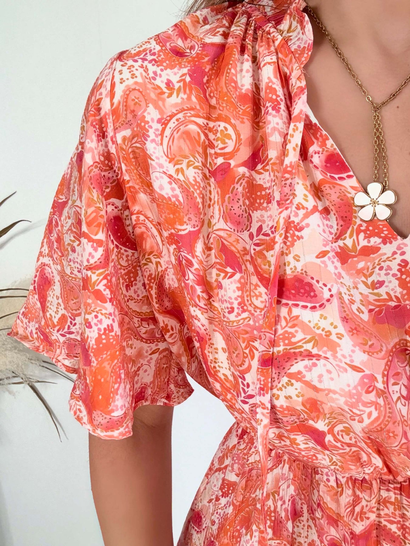 Robe corail à volants Solea, robe courte fluide à imprimé cachemire corail et rose, manches courtes évasées, taille élastiquée et jupe à volants. Modèle féminin et léger idéal pour les journées d’été.