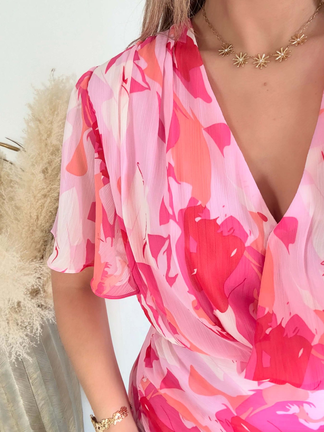 Robe courte rose imprimée Calista avec décolleté cache-cœur, manches fluides et jupe volantée.