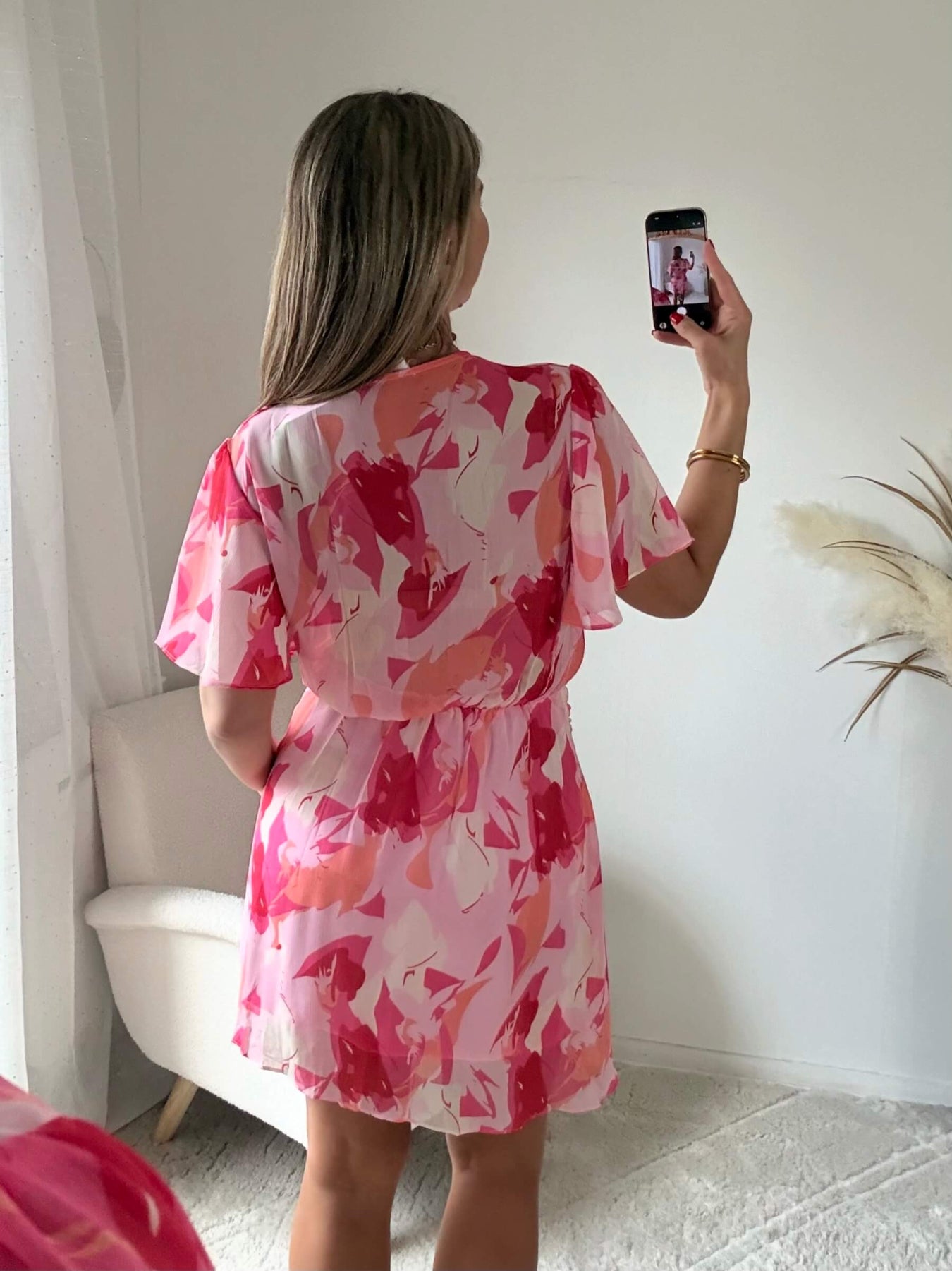 Robe courte rose imprimée Calista avec décolleté cache-cœur, manches fluides et jupe volantée.