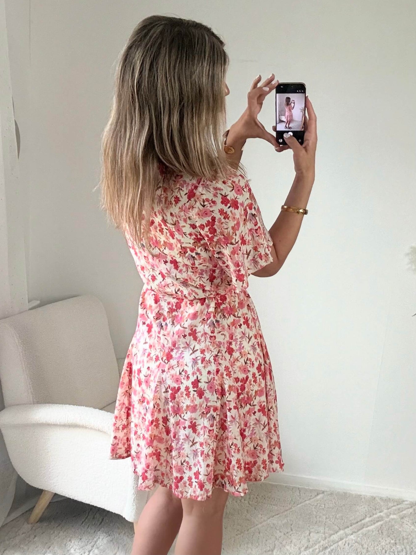 Robe courte corail fleurie Lyséa à manches courtes volantées et taille élastiquée, portée par un mannequin dans un intérieur lumineux.
