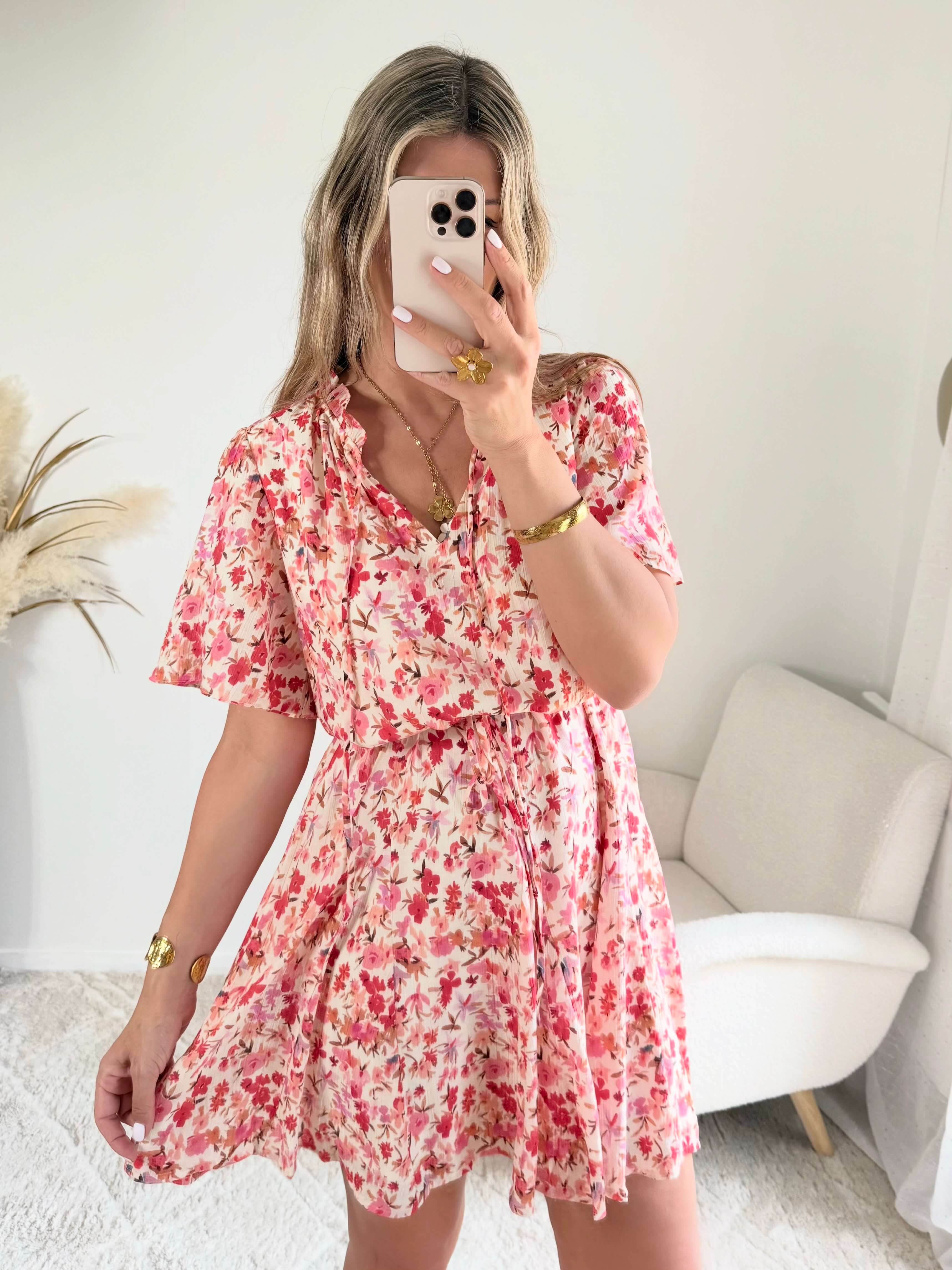 Robe courte corail fleurie Lyséa à manches courtes volantées et taille élastiquée, portée par un mannequin dans un intérieur lumineux.
