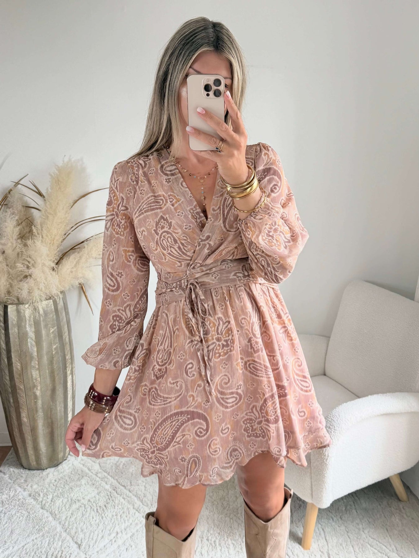 Robe courte Oxane rose poudré à imprimé cachemire, du S au 4XL, avec décolleté cache-cœur et jupe à volants, portée avec des bottes beiges.