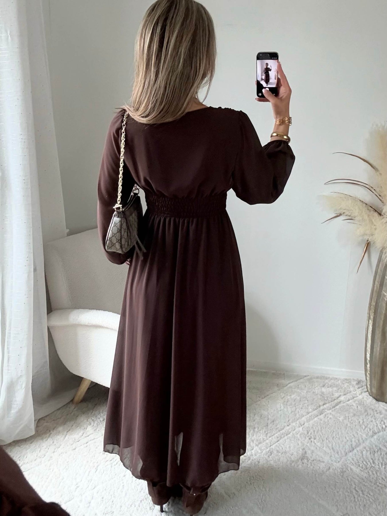 Robe longue fendue Lyana marron, décolleté cache-cœur et manches longues, portée avec des bottes marron.