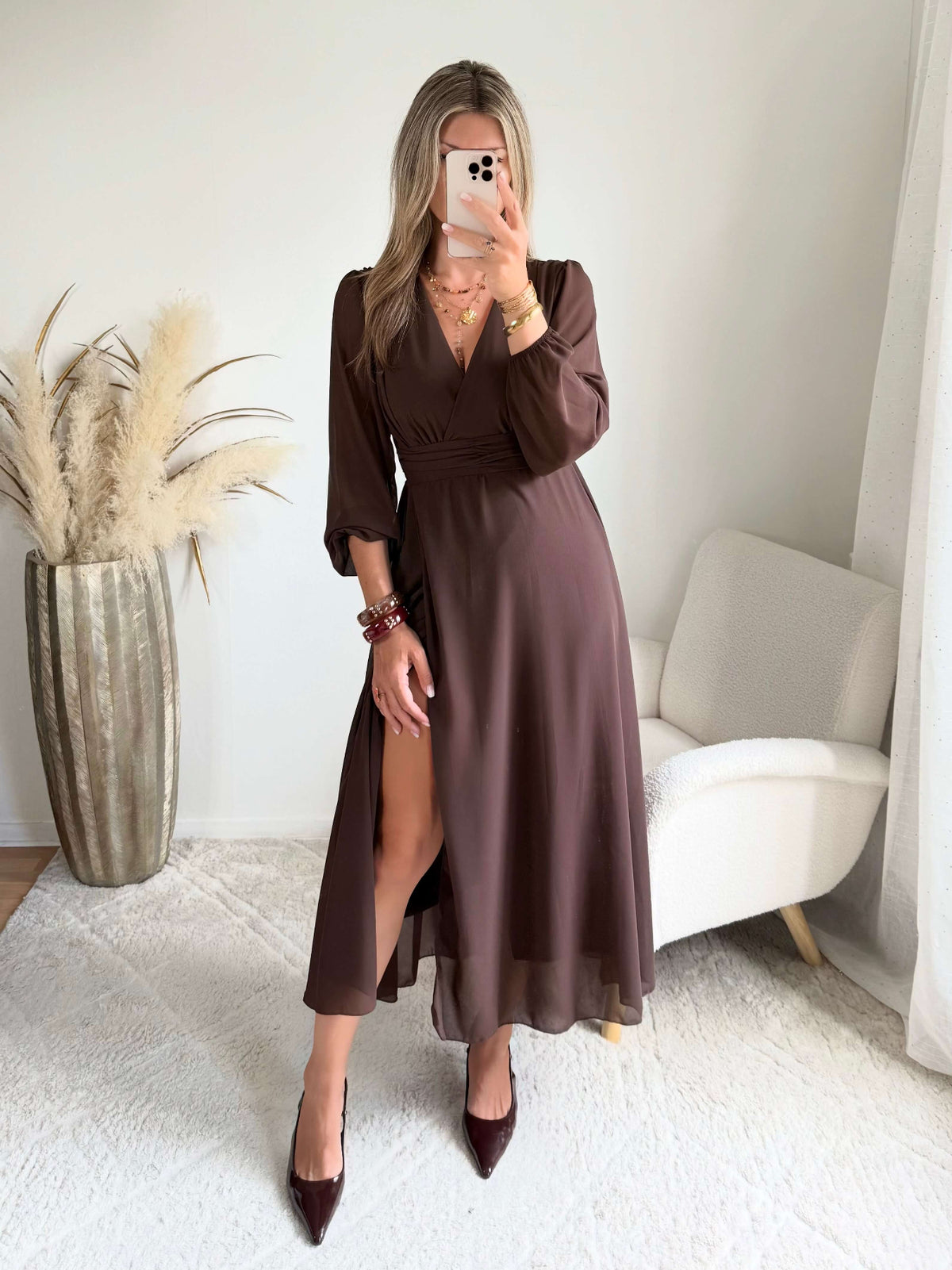 Robe longue fendue Lyana marron, décolleté cache-cœur et manches longues, portée avec des bottes marron.