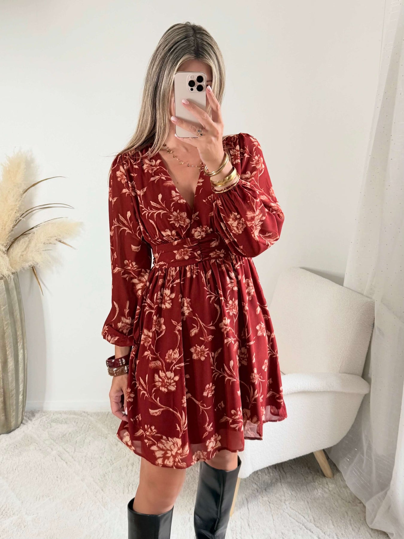 Robe courte terracotta fleurie Gaby, disponible du S au 4XL, à manches longues et décolleté en V, portée avec des bottes noires.