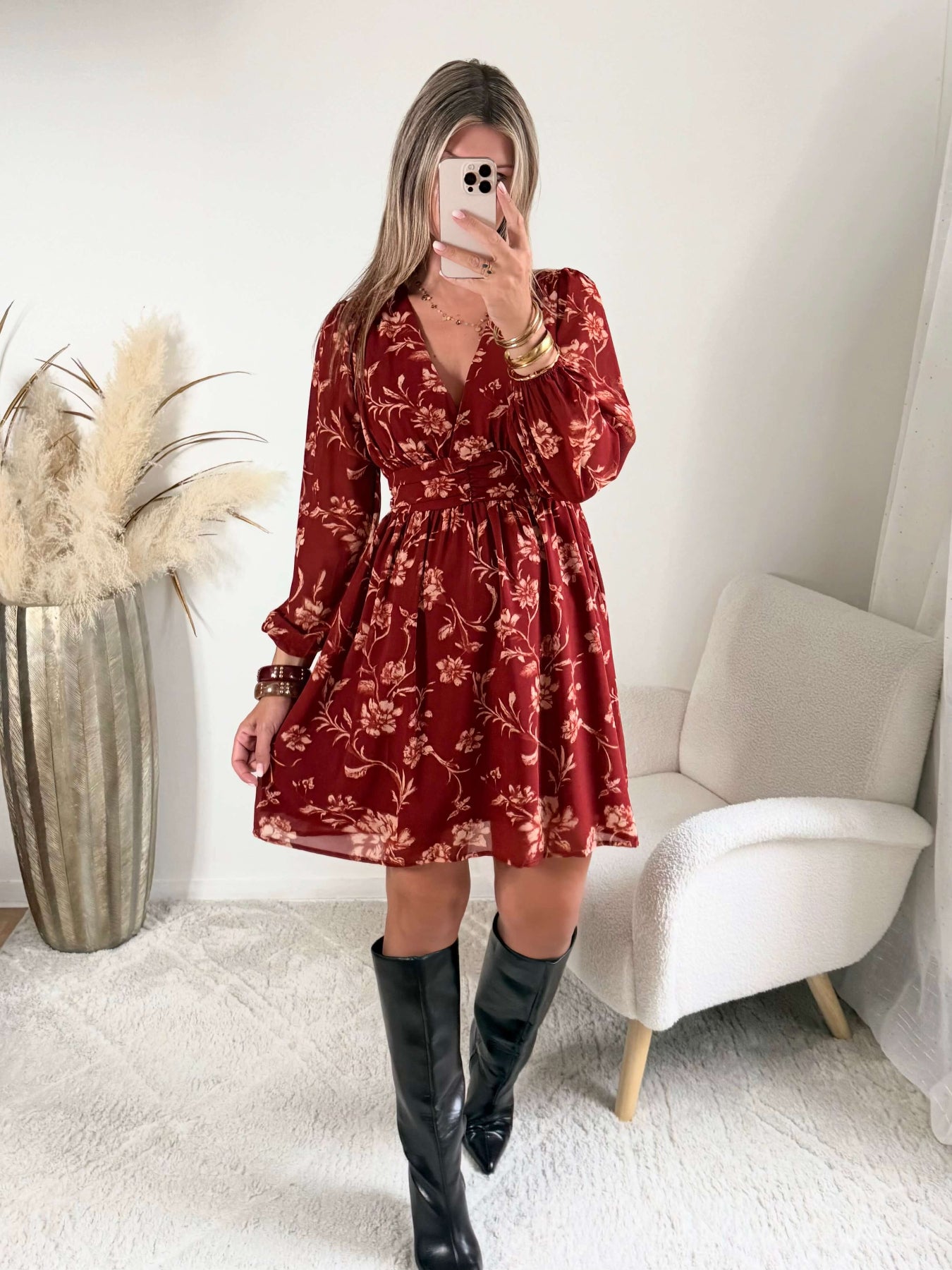 Robe courte terracotta fleurie Gaby, disponible du S au 4XL, à manches longues et décolleté en V, portée avec des bottes noires.