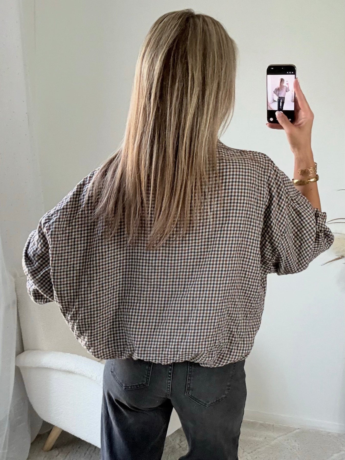 Femme portant le blouson court Tao à petits carreaux gris, marron et écru.