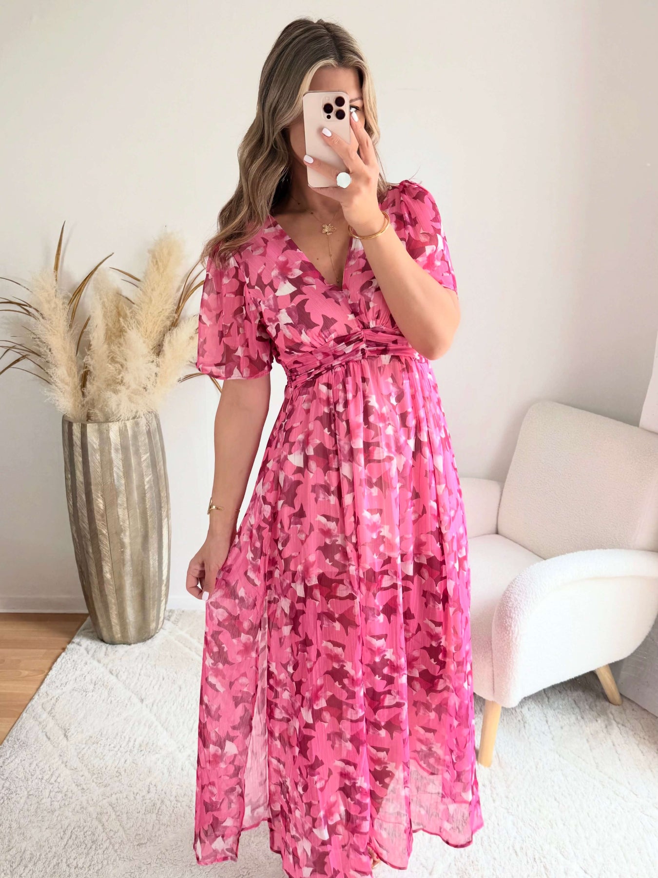 Robe longue plissée rose à imprimé floral avec manches fluides et décolleté croisé.
