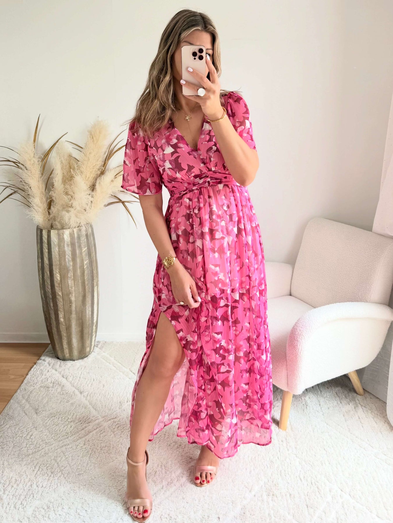 Robe longue plissée rose à imprimé floral avec manches fluides et décolleté croisé.