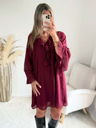Robe courte bordeaux Gloria du S au 4XL, portée sans ceinture, avec coupe ample, décolleté en V à volants et manches longues.