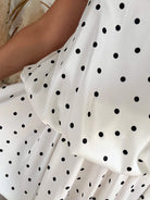 Robe courte Telma blanche à pois noirs avec dos nu et coupe fluide estivale.
