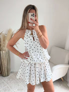 Robe courte Telma blanche à pois noirs avec dos nu et coupe fluide estivale.