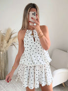 Robe courte Telma blanche à pois noirs avec dos nu et coupe fluide estivale.