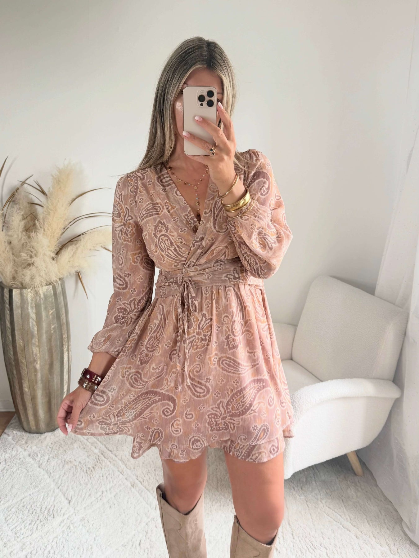 Robe courte Oxane rose poudré à imprimé cachemire, du S au 4XL, avec décolleté cache-cœur et jupe à volants, portée avec des bottes beiges.