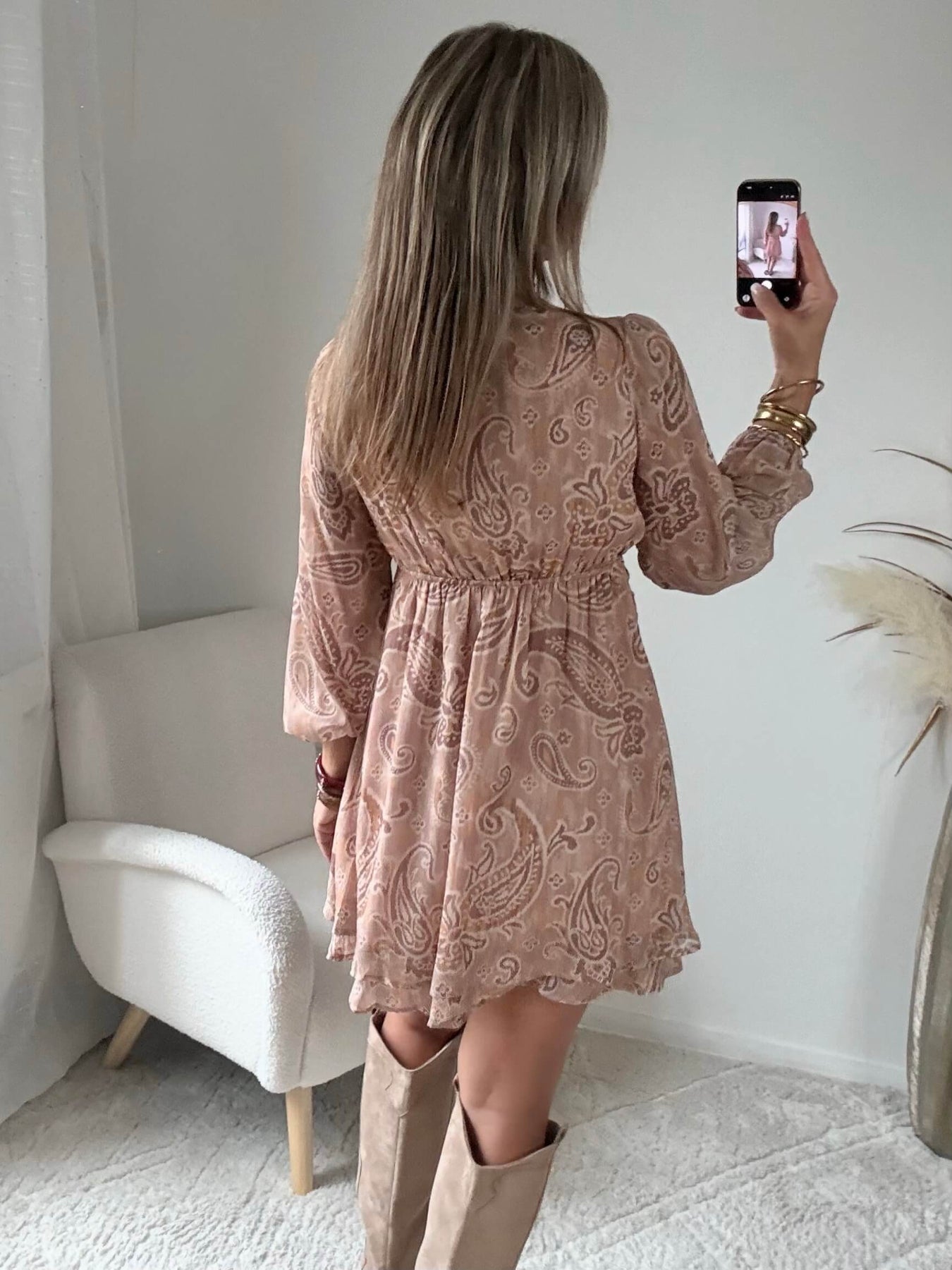 Robe courte Oxane rose poudré à imprimé cachemire, du S au 4XL, avec décolleté cache-cœur et jupe à volants, portée avec des bottes beiges.