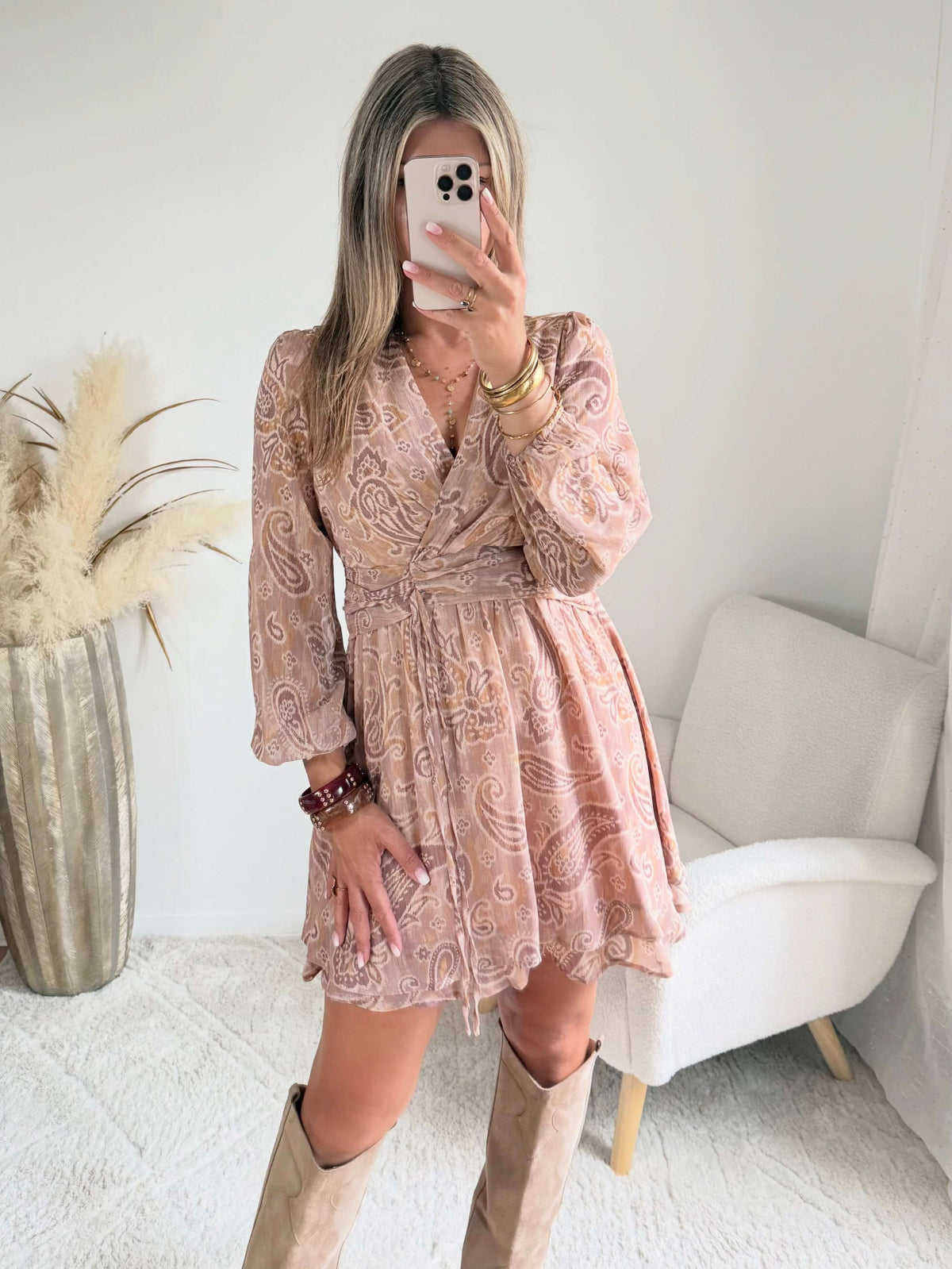 Robe courte Oxane rose poudré à imprimé cachemire, du S au 4XL, avec décolleté cache-cœur et jupe à volants, portée avec des bottes beiges.