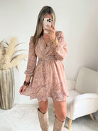 Robe courte Oxane rose poudré à imprimé cachemire, du S au 4XL, avec décolleté cache-cœur et jupe à volants, portée avec des bottes beiges.