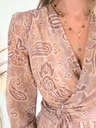 Robe courte Oxane rose poudré à imprimé cachemire, du S au 4XL, avec décolleté cache-cœur et jupe à volants, portée avec des bottes beiges.