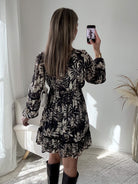 Robe courte noire Bella à imprimé floral écru, manches longues et taille élastiquée.
