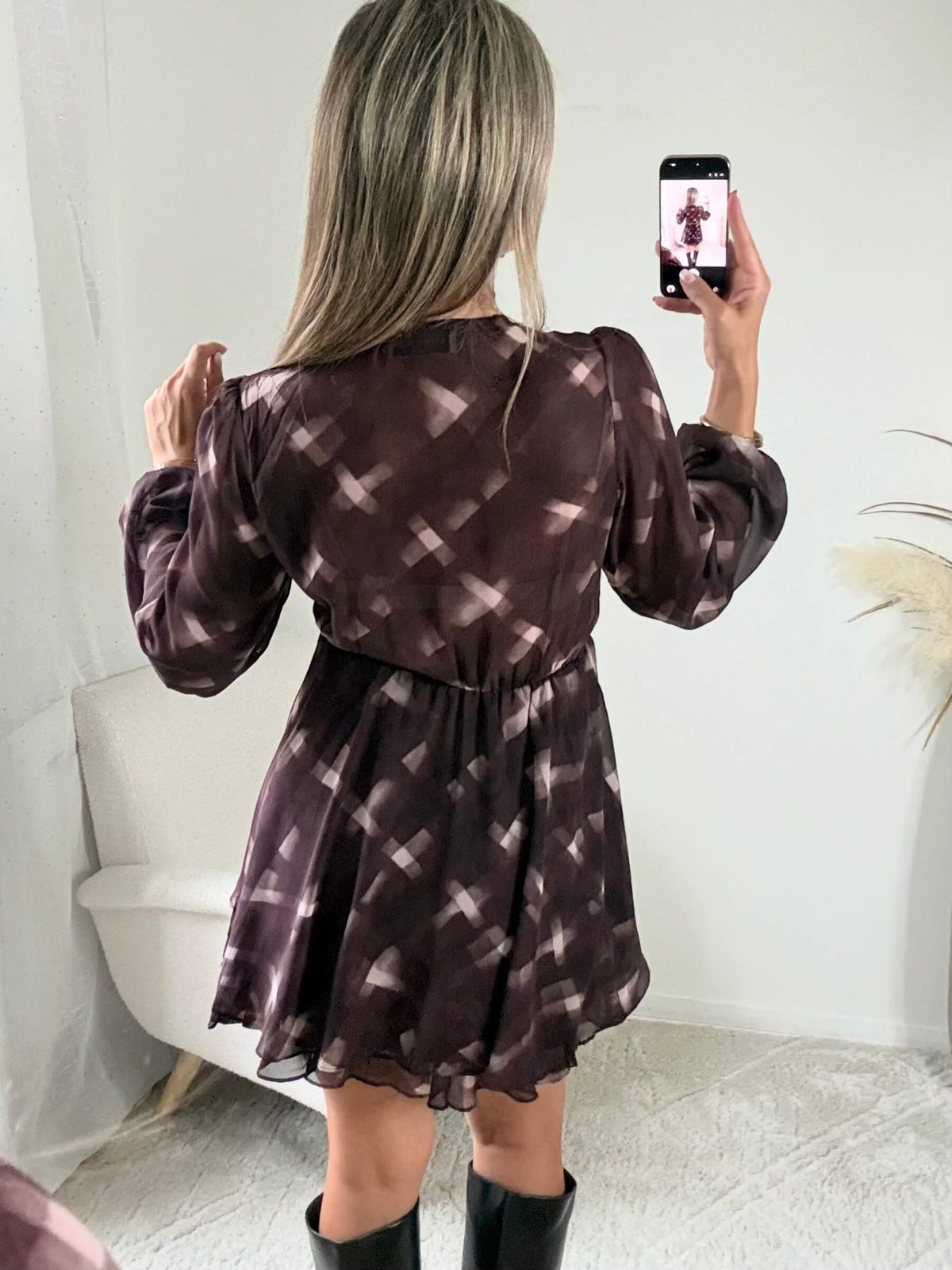 Femme portant la robe courte marron effet carreaux Joy avec taille ceinturée et jupe à volants
