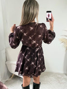 Femme portant la robe courte marron effet carreaux Joy avec taille ceinturée et jupe à volants