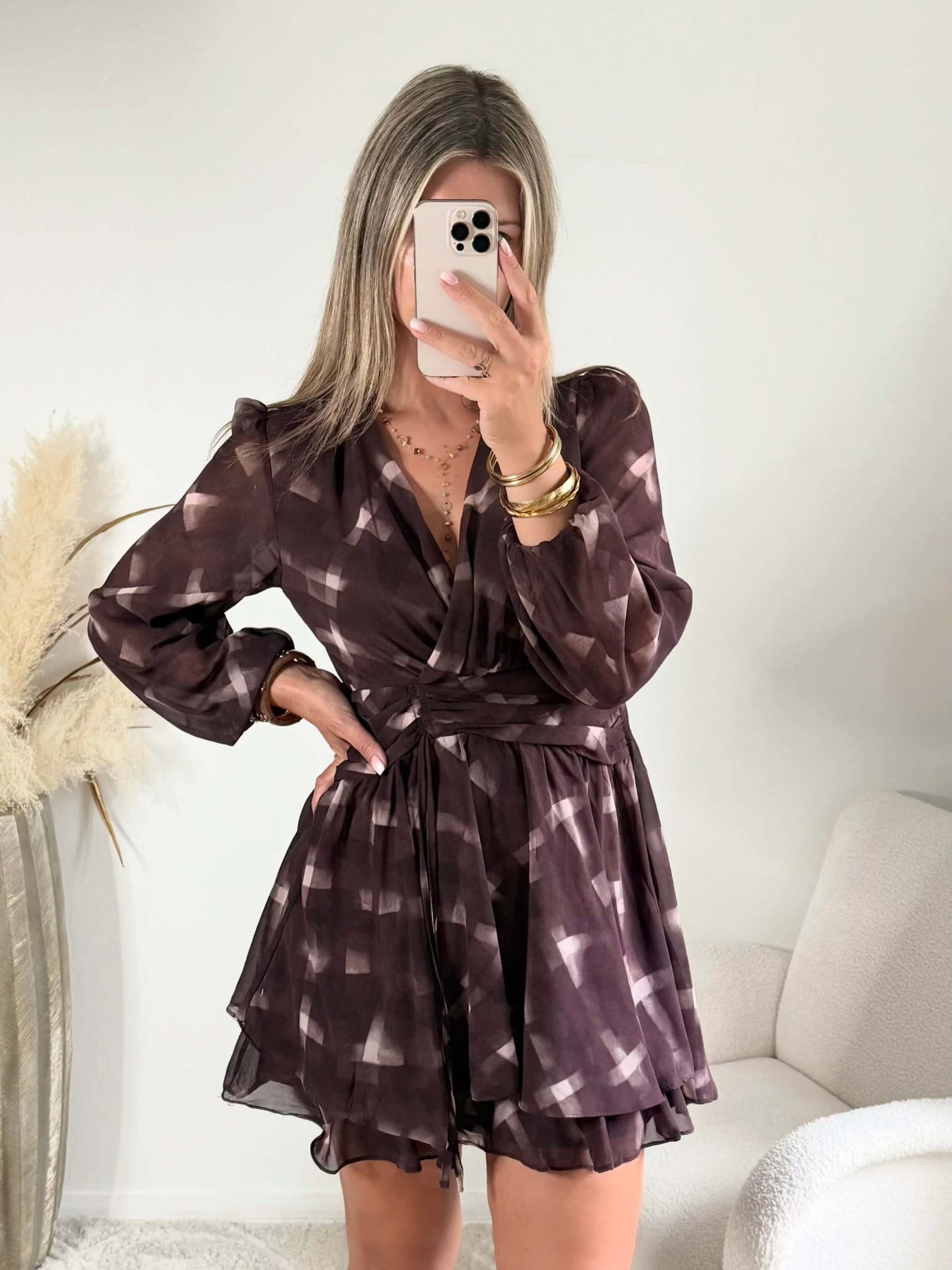 Femme portant la robe courte marron effet carreaux Joy avec taille ceinturée et jupe à volants