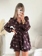 Femme portant la robe courte marron effet carreaux Joy avec taille ceinturée et jupe à volants