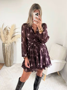 Femme portant la robe courte marron effet carreaux Joy avec taille ceinturée et jupe à volants