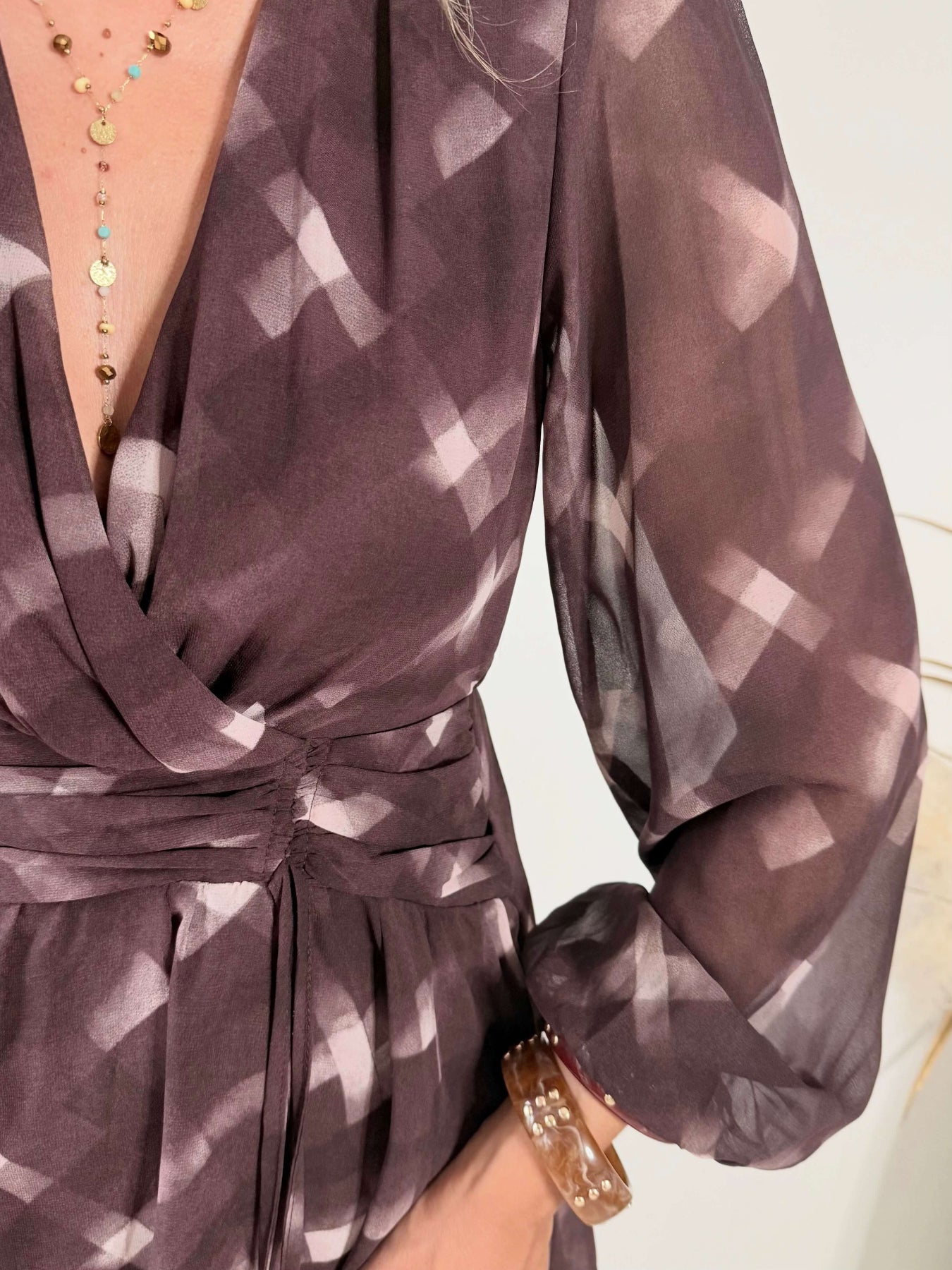 Femme portant la robe courte marron effet carreaux Joy avec taille ceinturée et jupe à volants