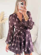 Femme portant la robe courte marron effet carreaux Joy avec taille ceinturée et jupe à volants