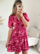 Robe courte fuchsia fleurie Guilia pour femme, coupe portefeuille, manches courtes, idéale pour les cérémonies, mariages et occasions estivales.