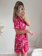 Robe courte fuchsia fleurie Guilia pour femme, coupe portefeuille, manches courtes, idéale pour les cérémonies, mariages et occasions estivales.