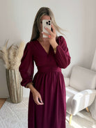 Femme portant la robe longue bordeaux Zoé à manches longues, décolleté cache-cœur et taille froncée.