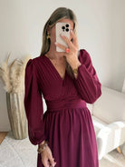 Femme portant la robe longue bordeaux Zoé à manches longues, décolleté cache-cœur et taille froncée.