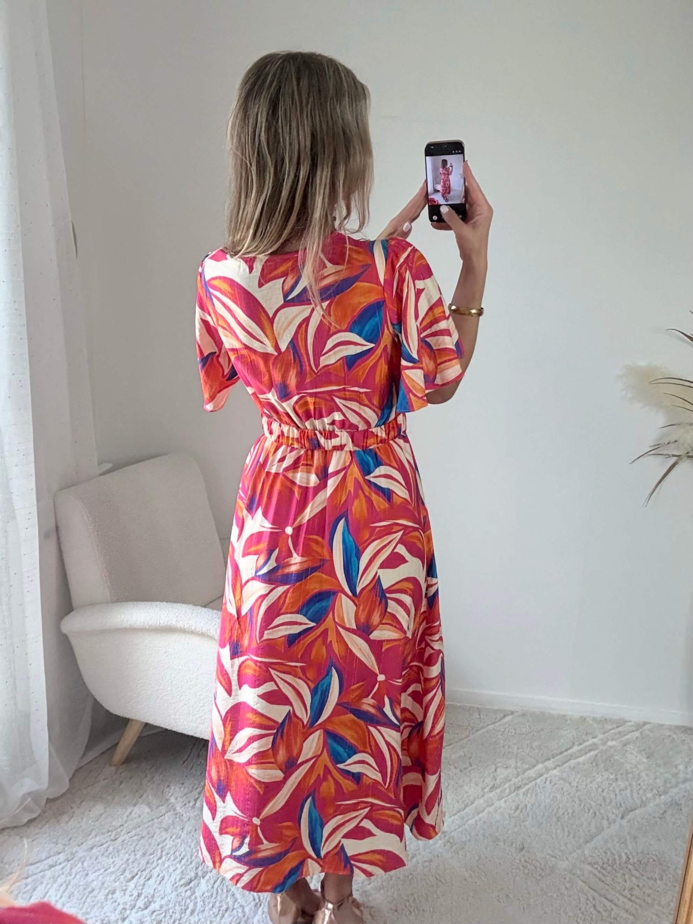 Robe longue imprimé tropical rose fuchsia, corail et bleu avec manches courtes et décolleté cache-cœur.