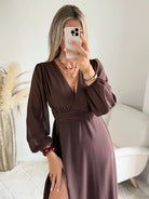 Robe longue fendue Lyana marron, décolleté cache-cœur et manches longues, portée avec des bottes marron.