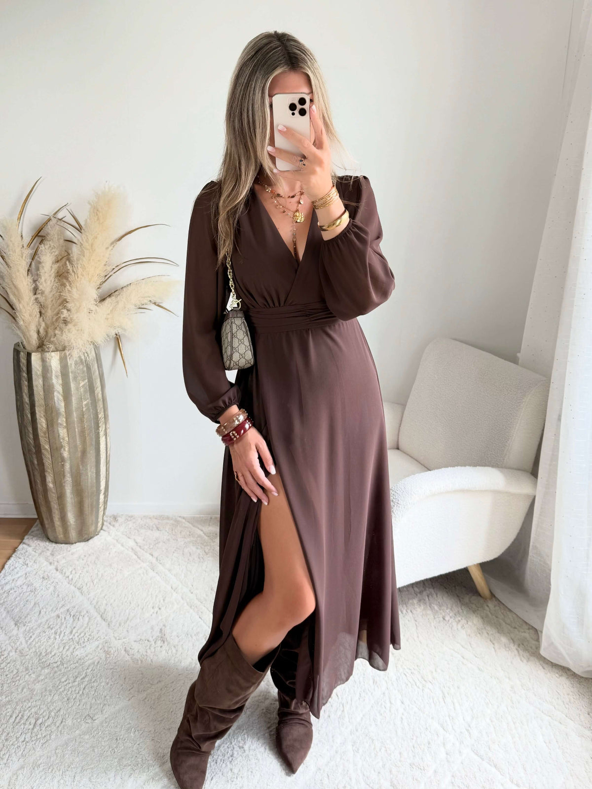 Robe longue fendue Lyana marron, décolleté cache-cœur et manches longues, portée avec des bottes marron.