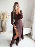 Robe longue fendue Lyana marron, décolleté cache-cœur et manches longues, portée avec des bottes marron.