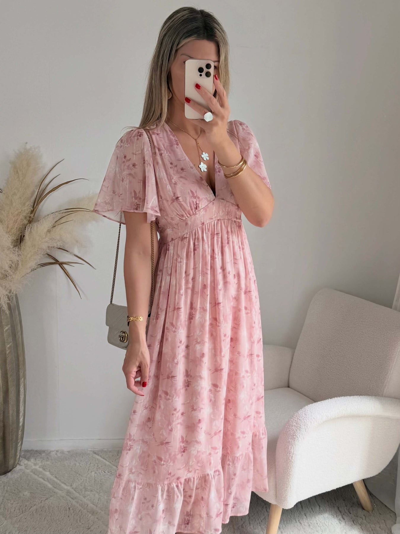 Robe longue rose poudré fleurie Naëlle avec manches fluides et décolleté cache-cœur portée par une femme.