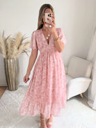 Robe longue rose poudré fleurie Naëlle avec manches fluides et décolleté cache-cœur portée par une femme.