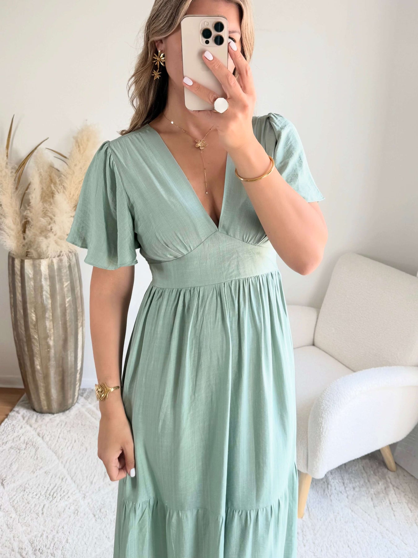 Femme portant une robe longue vert sauge fluide avec manches courtes et décolleté cache-cœur, style bohème chic.