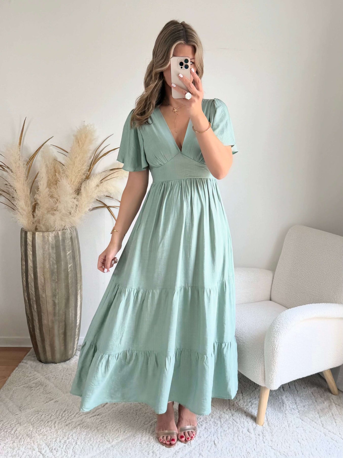 Femme portant une robe longue vert sauge fluide avec manches courtes et décolleté cache-cœur, style bohème chic.