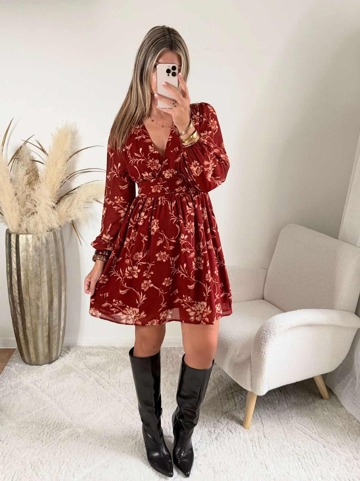 Robe courte terracotta fleurie Gaby, disponible du S au 4XL, à manches longues et décolleté en V, portée avec des bottes noires.