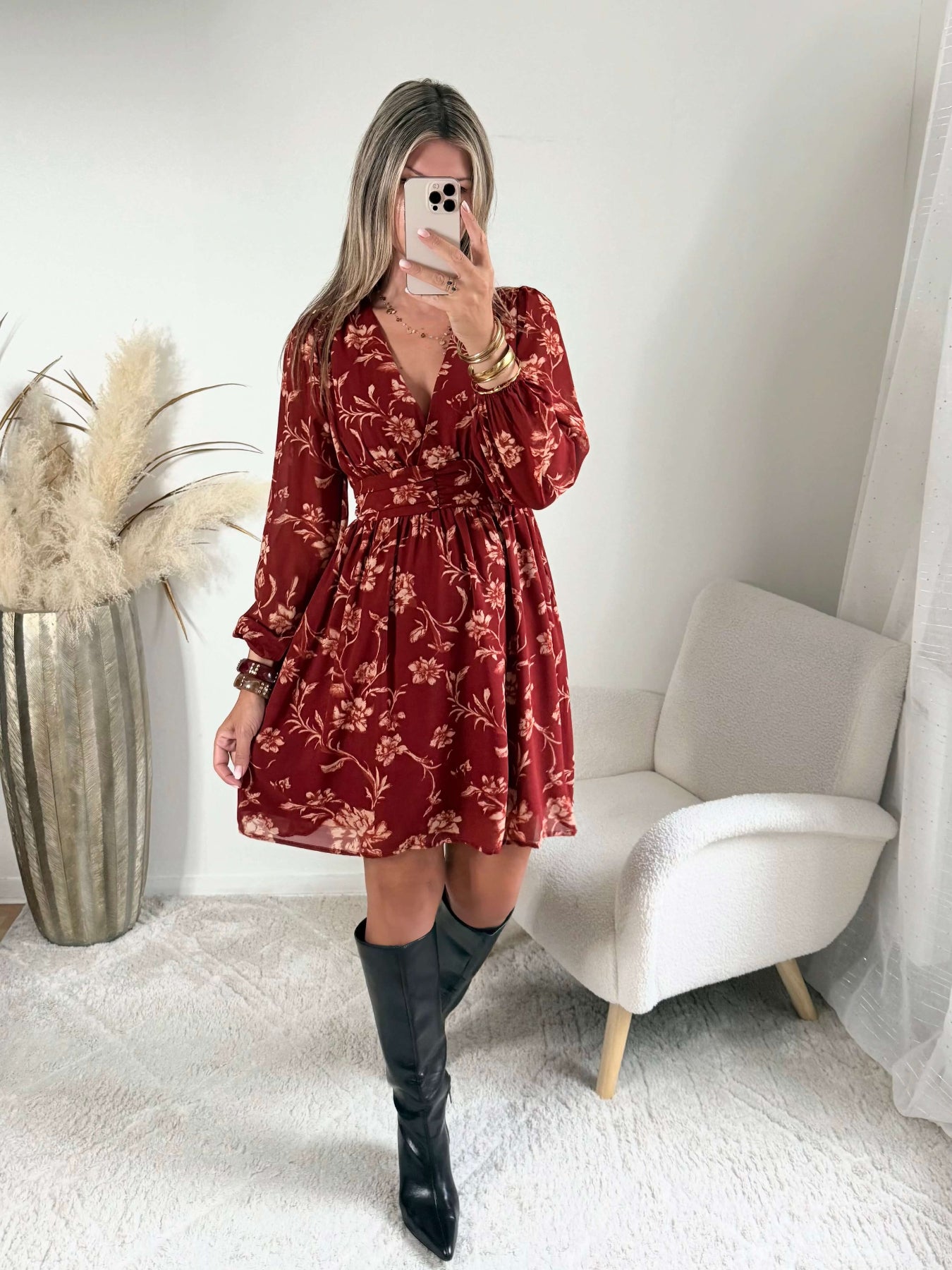 Robe courte terracotta fleurie Gaby, disponible du S au 4XL, à manches longues et décolleté en V, portée avec des bottes noires.