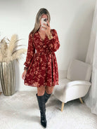 Robe courte terracotta fleurie Gaby, disponible du S au 4XL, à manches longues et décolleté en V, portée avec des bottes noires.