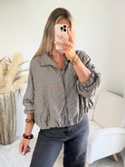 Femme portant le blouson court Tao à petits carreaux gris, marron et écru.