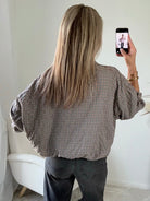 Femme portant le blouson court Tao à petits carreaux gris, marron et écru.
