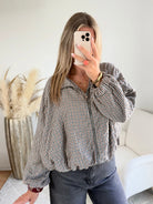 Femme portant le blouson court Tao à petits carreaux gris, marron et écru.