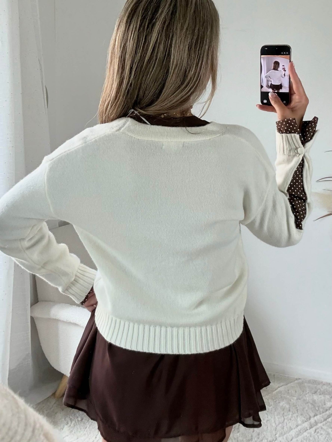 Cardigan écru aussi doux qu’original. Avec des empiècements marrons à petits pois.