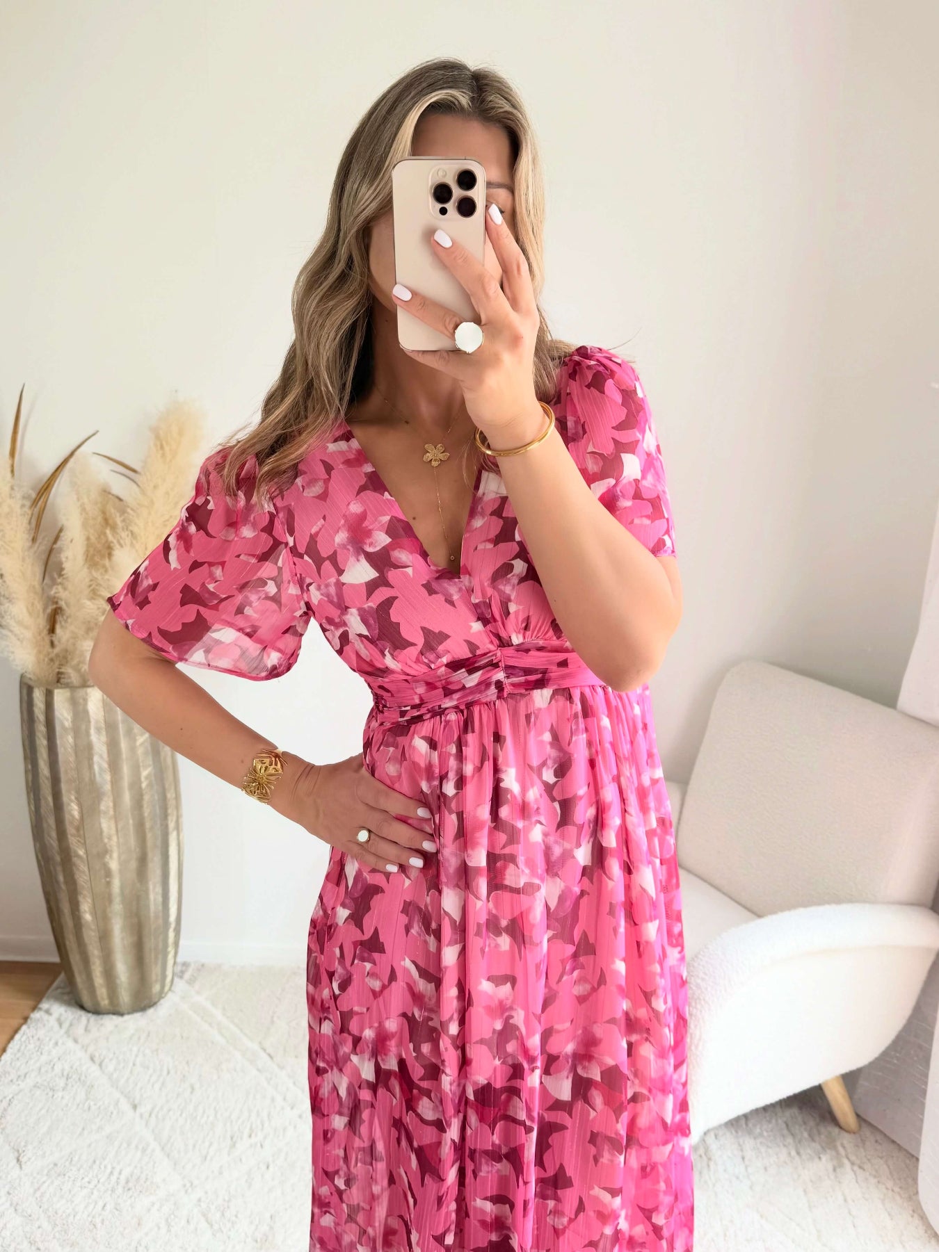 Robe longue plissée rose à imprimé floral avec manches fluides et décolleté croisé.